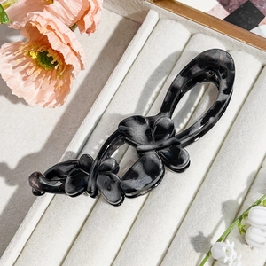 Detail showing marble texture butterfly banana hair clip in a plush display slot