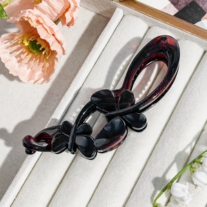 Detail of red and black gradient banana hair clip with 3D resin butterfly decor