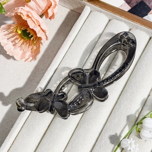 Polished smoke gray double butterfly banana clip on elegant white jewelry display