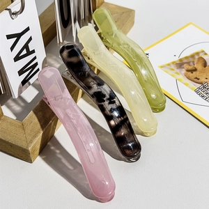 Nahaufnahme von vier Bananen-Haarspangen aus Harz in Rosa, Bernstein, Gelb und Grün