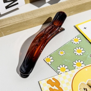 Makro-Detail der bernsteinfarbenen Harz-Haarklammer mit feinen Zähnen und glänzender Optik