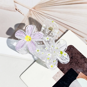 Detail of floral hair claw clip featuring real embedded white dried flowers and resin petals