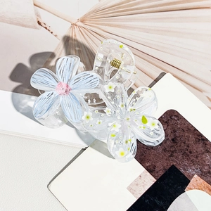 Detailed close-up of translucent floral hair claws with blue petals and white dried flowers