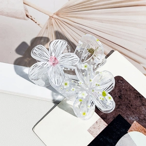 Detailed close-up of floral resin hair claw with white petals and golden spring detail
