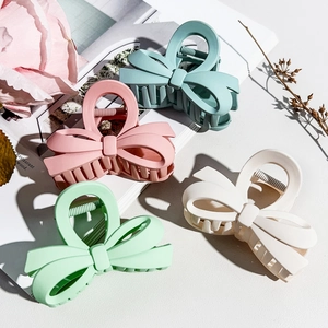 Macro shot of matte finish bow hair claws in pastel colors for elegant hair styling