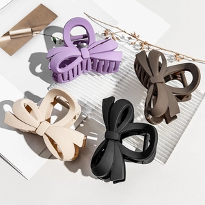 Detailed view of matte bow hair claws in purple, brown, beige, and black colors