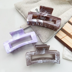 Detailed close-up of marble pattern claw clips in purple, brown and grey acetate