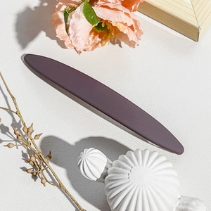 Close-up of a matte dark red barrette on a white leather texture with floral decor