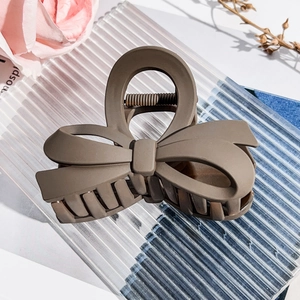 Detailed view of a matte brown bow hair claw clip placed on a textured glass tray
