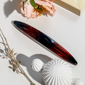 Detailed view of glossy gradient red acetate spring hair clip on decorative background