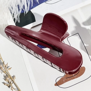 Dettaglio della pinza per capelli bordeaux lucido con design geometrico e minimalista