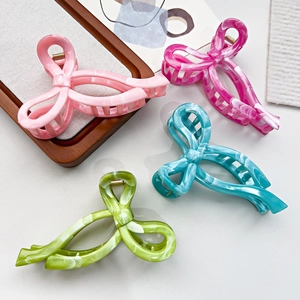 Detail view of four marble texture butterfly hair claws in pink, blue, and green acetate
