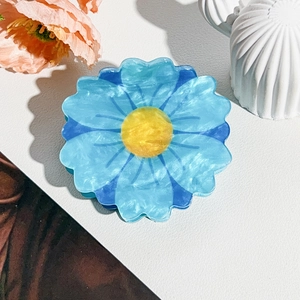 Detail of blue daisy hair claw clip with marble texture resin petals and yellow center