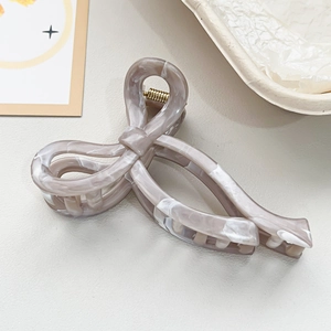 Detailed macro view of bow-shaped marble hair claw clip with golden metal spring