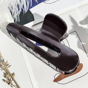 Dettaglio di un fermaglio per capelli marrone cioccolato lucido con grande design traforato