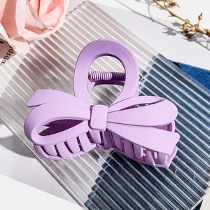 Detail shot of a matte purple bow hair claw clip placed on a decorative glass tray