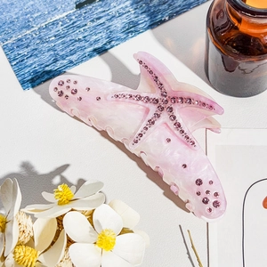 Close-up of pink starfish hair claw with marble texture and sparkling rhinestones