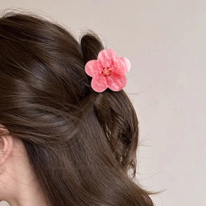 Pink sunflower hair claw clip with marble texture on long brown hair from back view