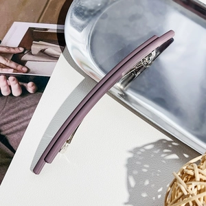 Close-up of matte Morandi purple hair clip on a textured white background with natural light