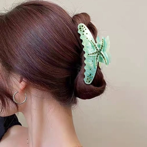 Woman wearing a mint green acetate starfish hair claw with green rhinestones for updo hair
