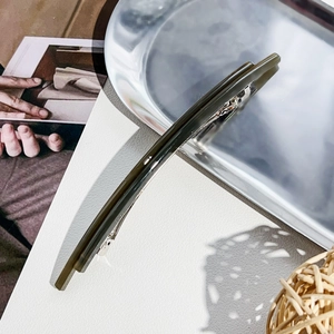 Minimalist olive green acetate spring hair clip on a premium metallic silver tray display