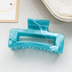 Close-up of square hair claw clip featuring teal and white marble texture with glossy finish
