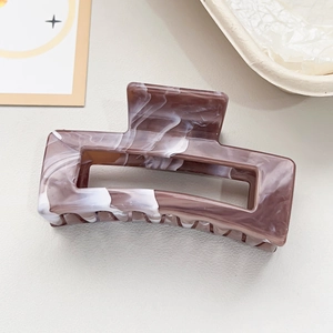 Detail shot of marble textured brown hair claw clip with acetate finish on soft background