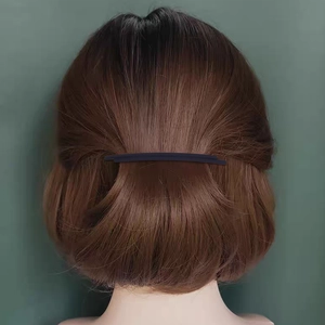 Minimalist black spring hair clip worn on brown short hair with a dark green background