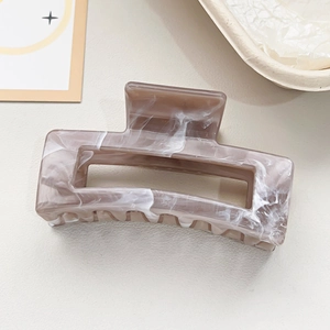 Detail of square marble pattern hair claw clip with brown resin texture and teeth