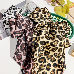 Three-pack leopard print bow hair clips with satin texture in a stylized storage basket