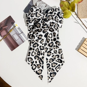 Detail of leopard print bow hair clip with long ribbons on a decorative background