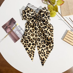 Detailed view of leopard print bow hair clip with long ribbons on a white display