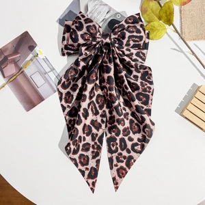 Detail of leopard print ribbon hair bow with premium satin texture and long streamers