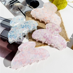 Macro detail of large resin hair claws with colorful mosaic patterns on a fabric background