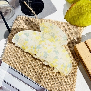 Close-up of butterfly claw clip with yellow and blue floral pattern on burlap