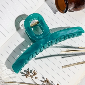 Détail d'une pince à cheveux en résine bleu cyan translucide avec ressort doré et marbre