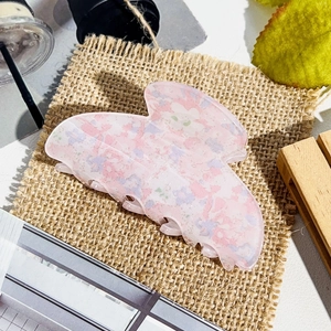 Close-up of pink floral daisy hair claw clip with acrylic texture on a rustic base