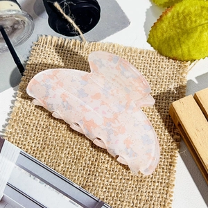 Detail of butterfly claw clip featuring floral marble pattern on a rustic background