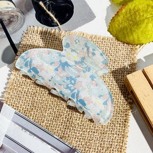 Detail view of butterfly hair claw clip with colorful floral marble pattern texture