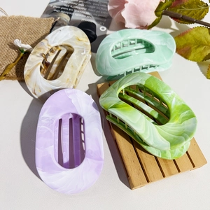 Detailed close-up of oval marble-patterned hair claws in four elegant gradient colors