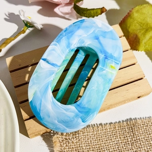 Close-up of marble pattern hair claw clip with blue and white acetate finish on wood