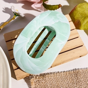 Detailed macro view of mint green marbled acetate hair claw clip on wooden stand