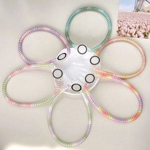 Set of six colorful gradient spiral hair ties displayed on a white shell ceramic dish
