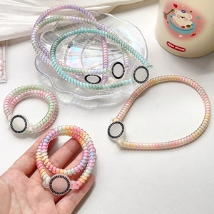 Close-up of pastel spiral hair ties and bracelets with decorative rings on glass plate