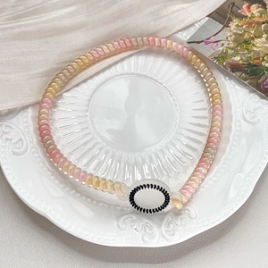Detail of pastel beaded phone cord hair tie on an elegant white plate background