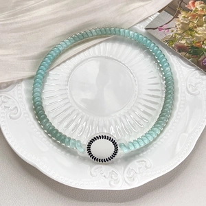 Detail of light green telephone wire hair tie with white round charm on white plate