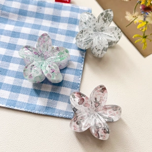 Vue détaillée de trois pinces à cheveux fleurs en résine avec motifs colorés variés