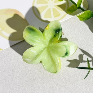 Gros plan sur une pince à cheveux fleur de frangipanier aux motifs marbrés