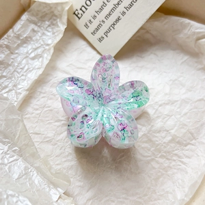 Détail de la pince à cheveux fleur avec texture marbrée colorée sur papier crème