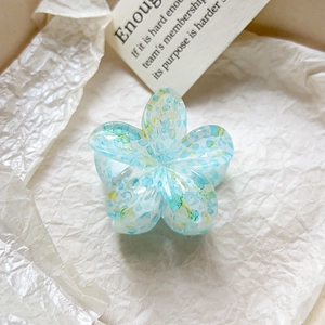Vue détaillée du motif floral bleu translucide sur la pince à cheveux en forme de fleur